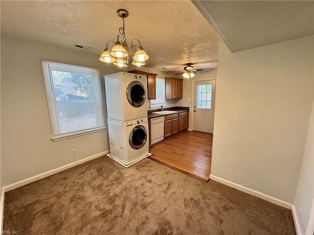 laundry area with stacked washer / dryer, a sink, visible vents, baseboards, and carpet