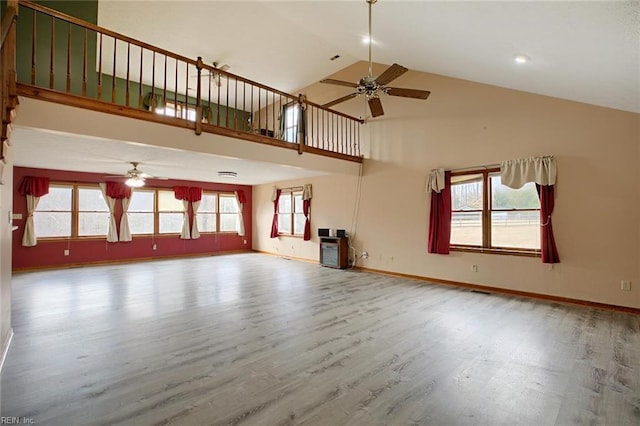 unfurnished living room with high vaulted ceiling, a ceiling fan, baseboards, and wood finished floors