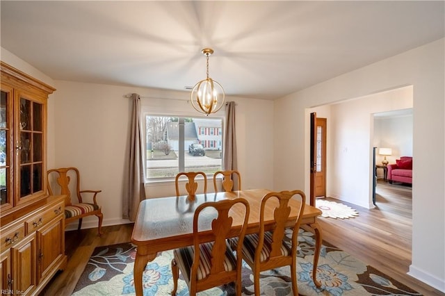 dining room featuring baseboards, light wood finished floors, and a notable chandelier