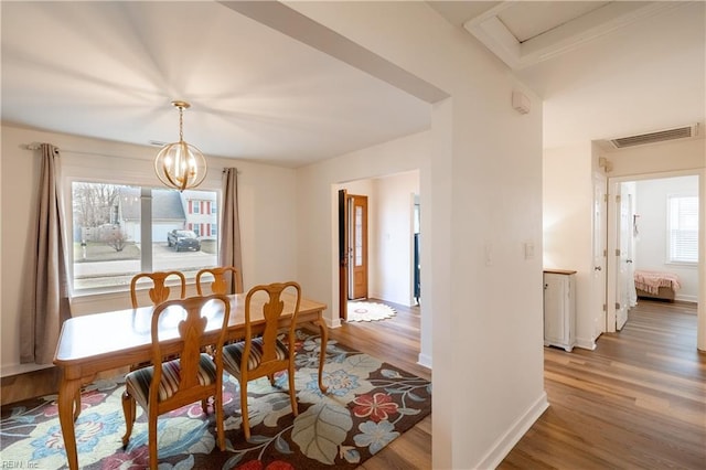 dining space featuring light wood-type flooring, an inviting chandelier, baseboards, and visible vents