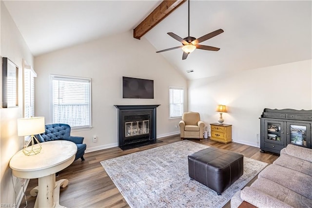 living area with lofted ceiling with beams, a fireplace with flush hearth, baseboards, and wood finished floors