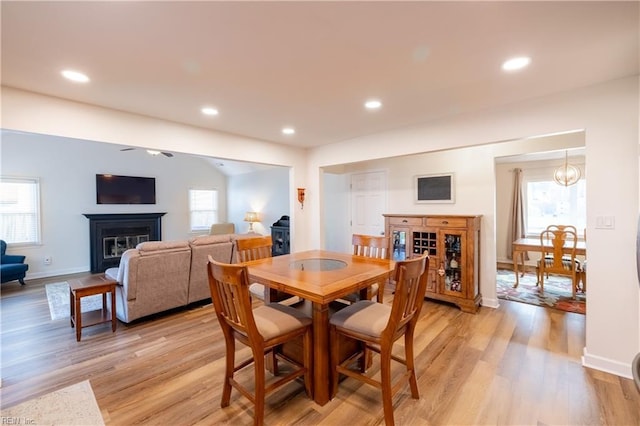 dining space featuring light wood-type flooring, a glass covered fireplace, and recessed lighting