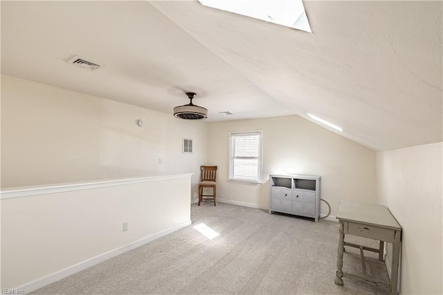 additional living space with light colored carpet, vaulted ceiling with skylight, visible vents, and baseboards