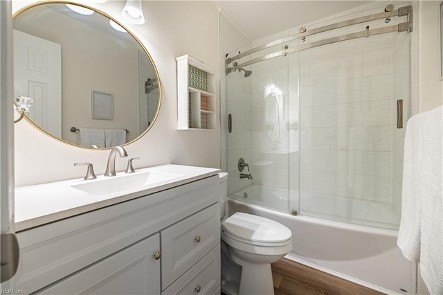 bathroom with toilet, combined bath / shower with glass door, wood finished floors, and vanity