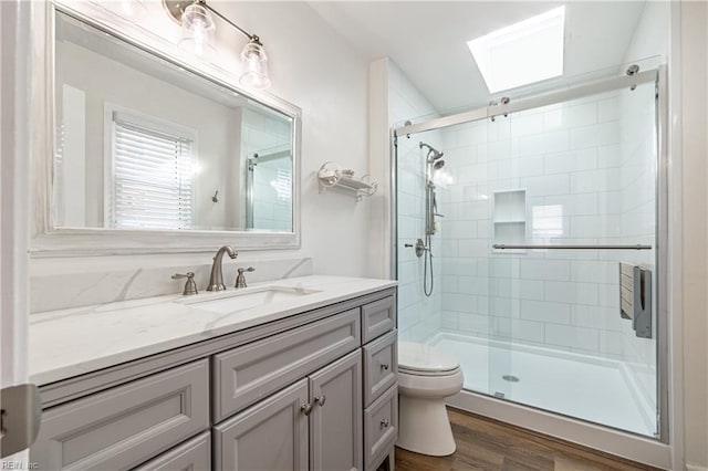 bathroom featuring a stall shower, vanity, toilet, and wood finished floors