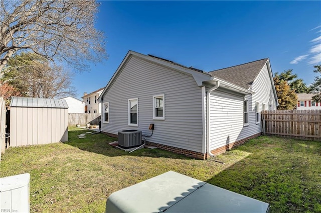 view of property exterior with a lawn, a fenced backyard, an outdoor structure, central air condition unit, and a shed