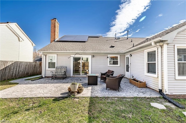 back of property with solar panels, fence, a yard, a chimney, and a patio area