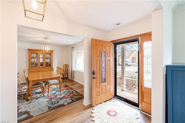 entryway with an inviting chandelier, visible vents, baseboards, and wood finished floors