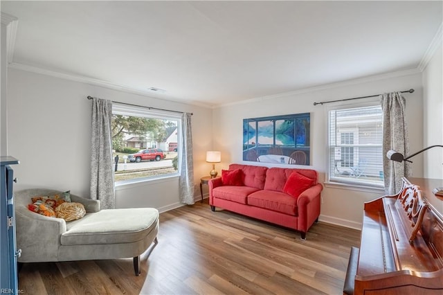 living area featuring baseboards, wood finished floors, visible vents, and crown molding