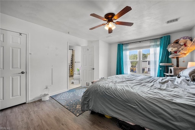 bedroom with baseboards, visible vents, ensuite bath, ceiling fan, and wood finished floors