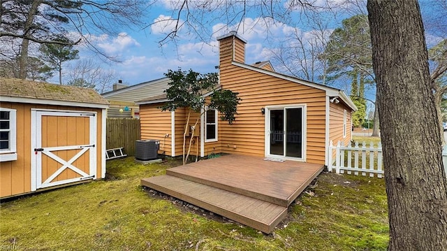 rear view of property featuring an outbuilding, a wooden deck, a yard, and fence