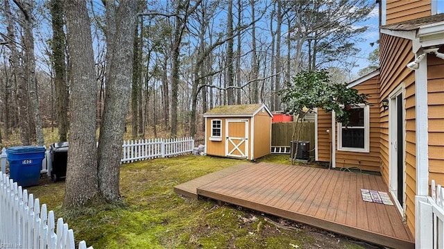 view of yard with a shed, cooling unit, a fenced backyard, a deck, and an outbuilding