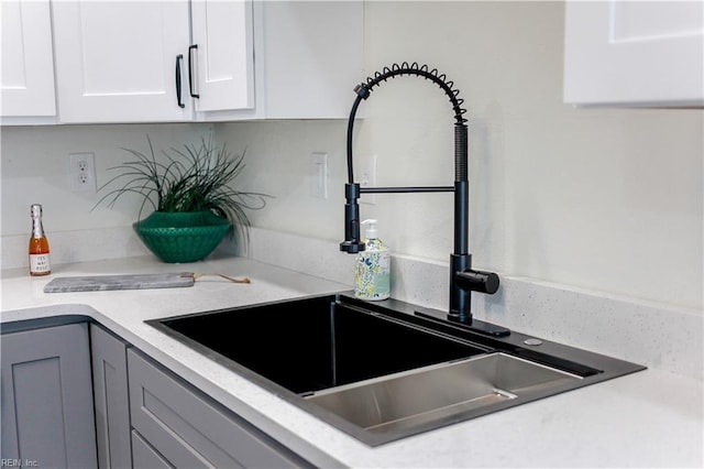 interior details featuring white cabinetry, light countertops, a sink, and gray cabinetry