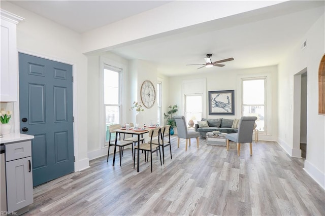 dining area featuring baseboards, ceiling fan, light wood-style flooring, and a healthy amount of sunlight