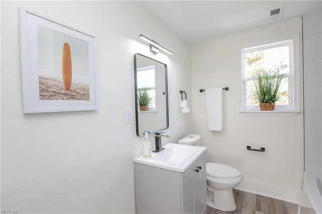 full bathroom with a wealth of natural light, visible vents, toilet, and wood finished floors