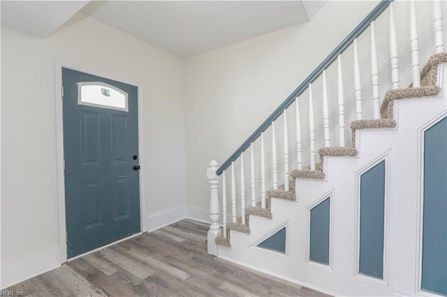 entryway with stairs, baseboards, and wood finished floors