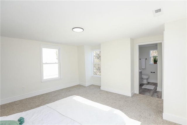 bedroom featuring light carpet, visible vents, baseboards, and ensuite bathroom