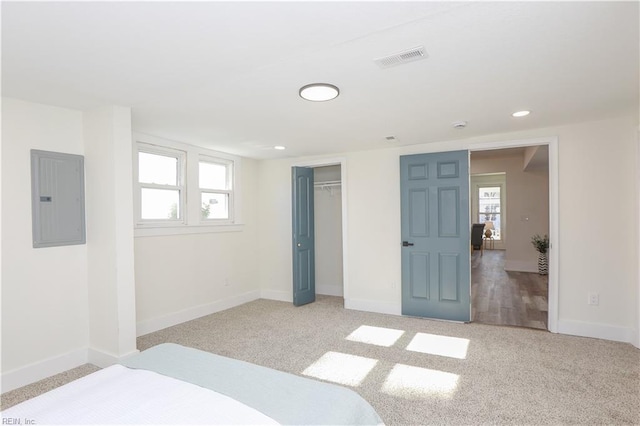 bedroom with visible vents, electric panel, light carpet, and baseboards