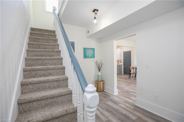 stairs with wood finished floors, visible vents, and baseboards