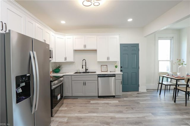 kitchen featuring appliances with stainless steel finishes, light wood-type flooring, light countertops, and a sink