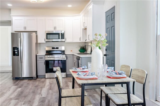 kitchen featuring appliances with stainless steel finishes, light countertops, gray cabinetry, light wood-style floors, and white cabinetry