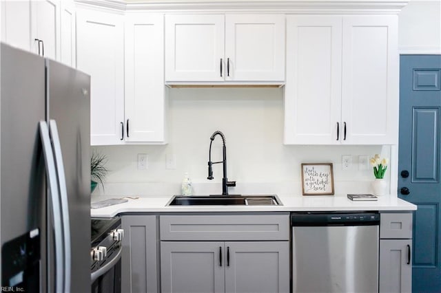 kitchen with light countertops, appliances with stainless steel finishes, a sink, and white cabinets