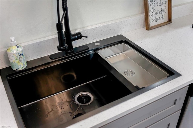 details featuring light stone counters, gray cabinets, and a sink