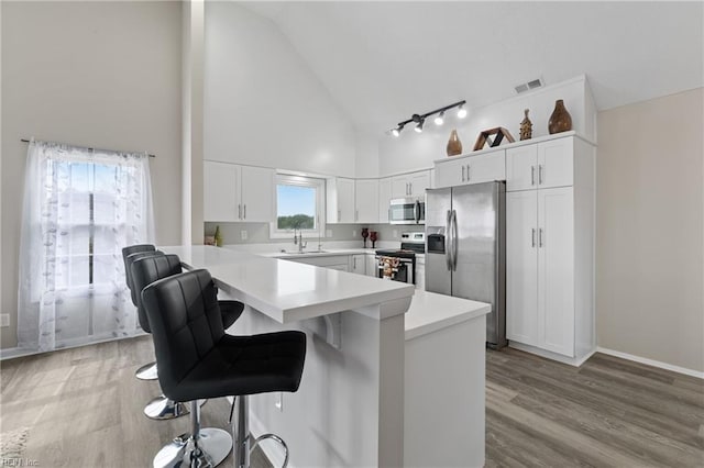 kitchen with visible vents, light countertops, white cabinets, appliances with stainless steel finishes, and a kitchen breakfast bar