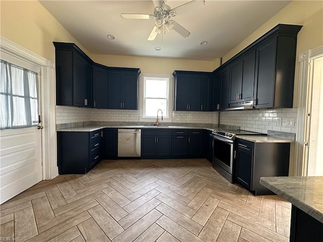 kitchen featuring decorative backsplash, ceiling fan, appliances with stainless steel finishes, under cabinet range hood, and a sink