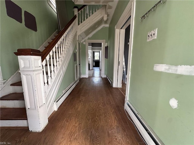 hall featuring a baseboard heating unit, dark wood-type flooring, stairway, and baseboard heating