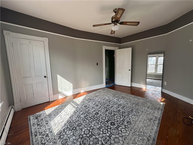 bedroom featuring a baseboard heating unit, wood finished floors, a ceiling fan, and baseboards