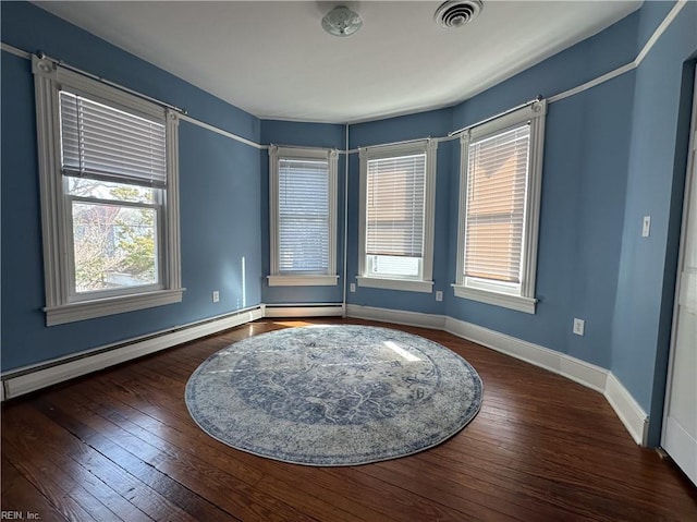 empty room with a baseboard radiator, wood-type flooring, visible vents, a baseboard heating unit, and baseboards