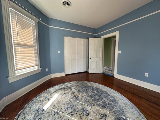 bedroom with baseboards, a closet, visible vents, and wood finished floors