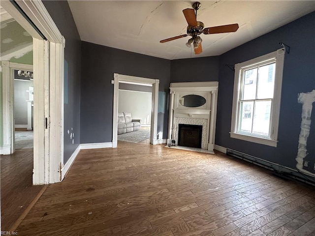 unfurnished living room with a fireplace with flush hearth, wood-type flooring, ceiling fan, and baseboards