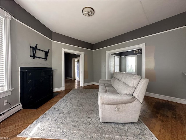 living room with a baseboard heating unit, baseboards, and hardwood / wood-style flooring