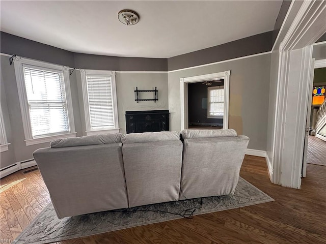 living area with a baseboard radiator, baseboards, and wood finished floors