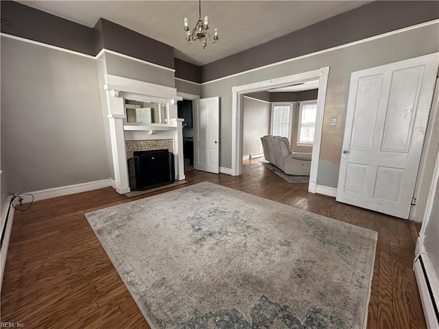 unfurnished living room with dark wood-style flooring, a fireplace with flush hearth, baseboards, baseboard heating, and an inviting chandelier