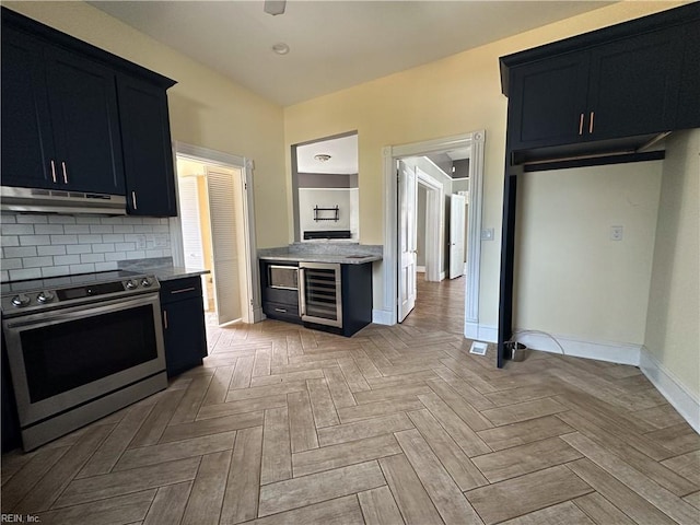 kitchen featuring dark cabinets, electric range, wine cooler, and under cabinet range hood