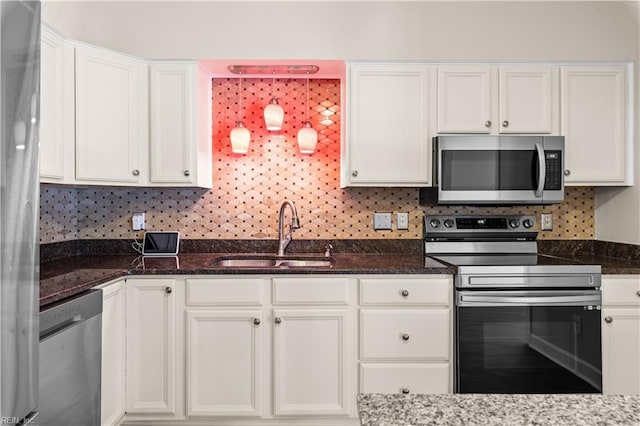 kitchen featuring white cabinetry, dark stone counters, appliances with stainless steel finishes, and a sink