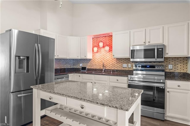 kitchen with tasteful backsplash, dark stone countertops, white cabinetry, and stainless steel appliances