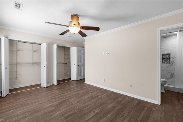 unfurnished bedroom with two closets, crown molding, baseboards, and wood finished floors