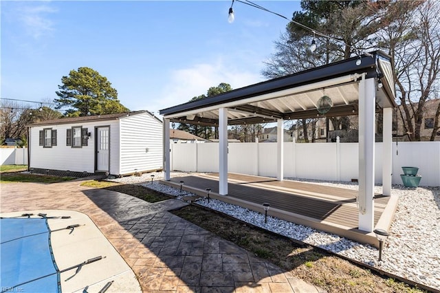 view of patio featuring an outdoor structure, a pool, and a fenced backyard