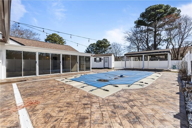 view of swimming pool featuring a patio, a fenced backyard, an outdoor structure, a sunroom, and a fenced in pool