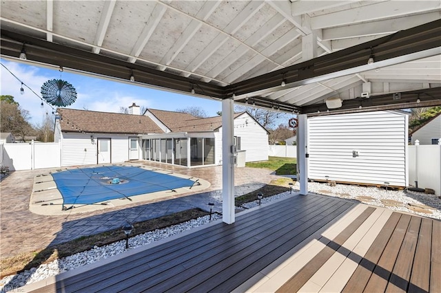 wooden terrace with a fenced in pool, a patio, an outbuilding, and a fenced backyard