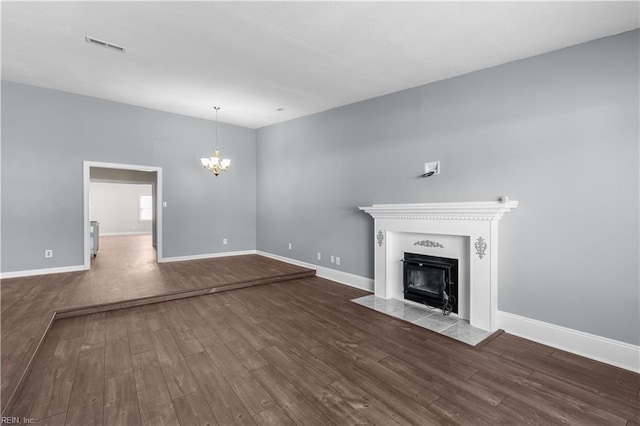 unfurnished living room with baseboards, a notable chandelier, and wood finished floors