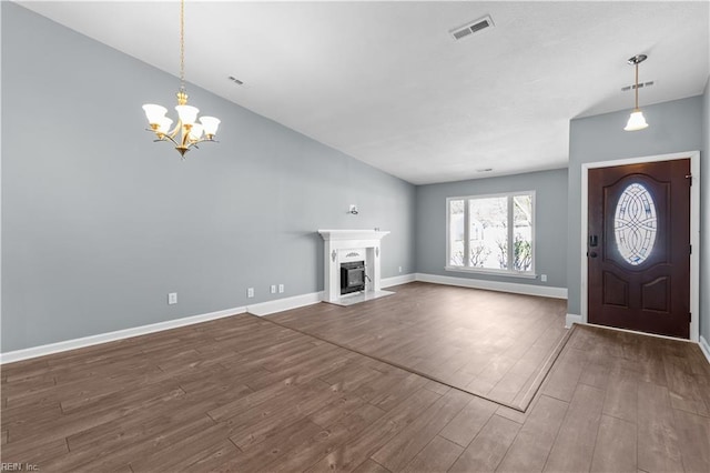 foyer with dark wood-style floors, visible vents, baseboards, an inviting chandelier, and a fireplace with flush hearth