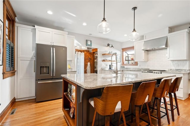 kitchen with visible vents, light wood finished floors, open shelves, stainless steel appliances, and wall chimney range hood