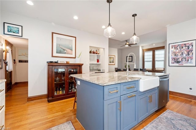 kitchen featuring pendant lighting, a sink, a fireplace, light wood finished floors, and dishwasher