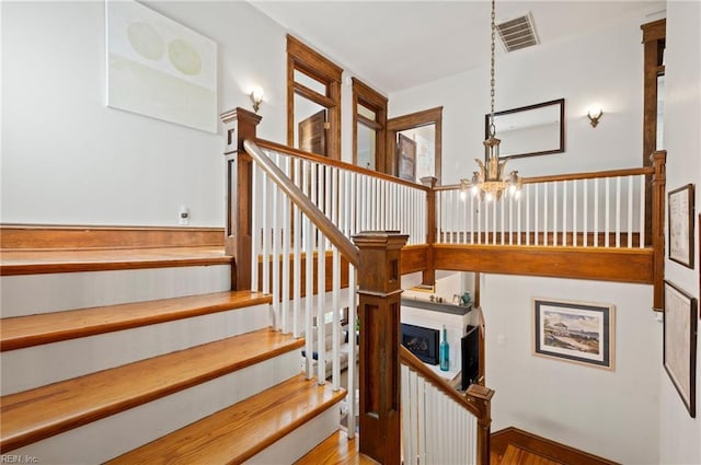 staircase featuring visible vents and an inviting chandelier