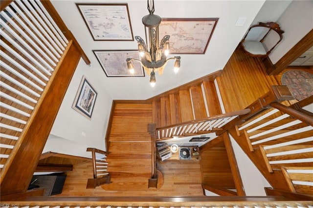 staircase featuring an inviting chandelier and wood finished floors